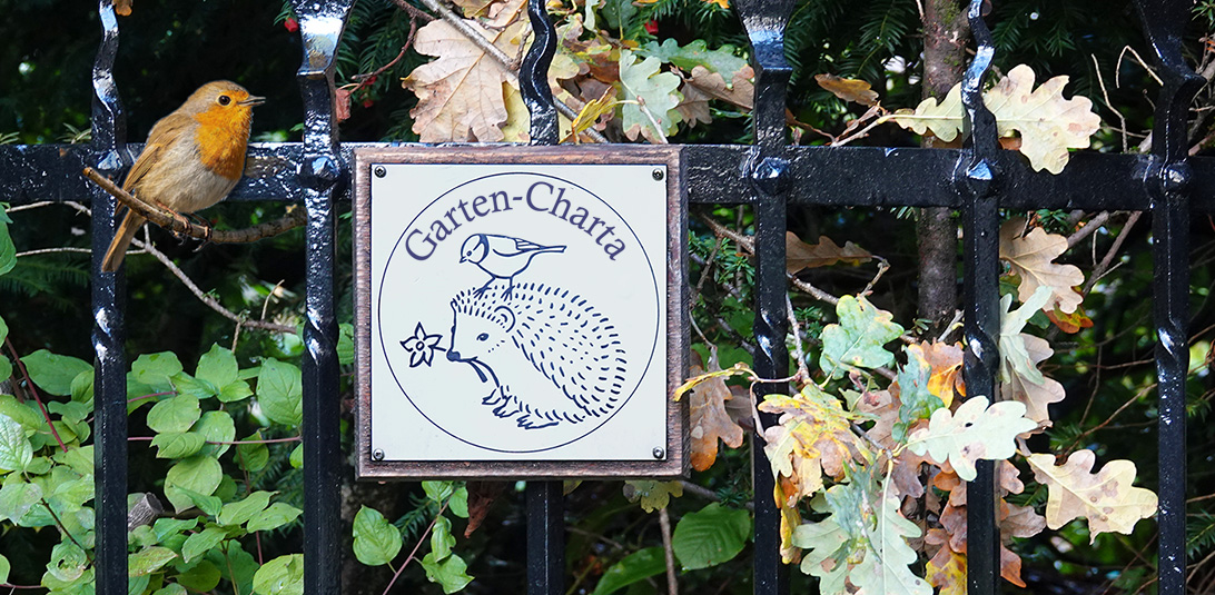 Emblem der Garten-Charta an einem Zaun
